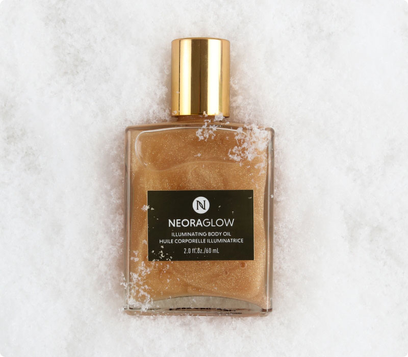 Neora’s hottest holiday limited-time must-have, Glisten Up Holiday Body Glow Oil, laying on a bed of snow!